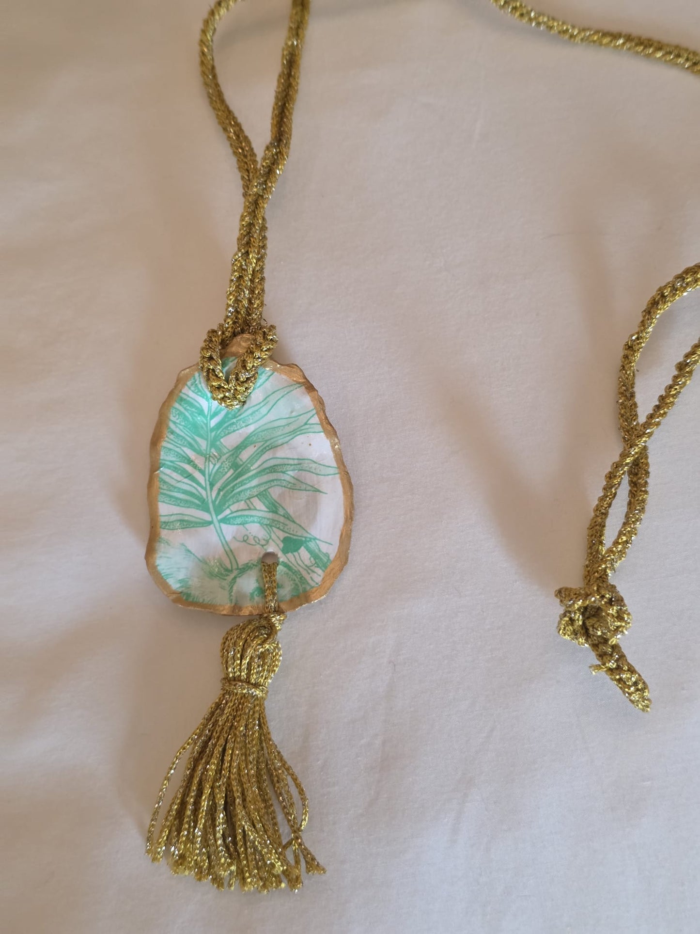 Collar artesanal con concha de ostión decorada con papel de arroz, cordón de ganchillo con hilo metalizado, pieza única inspirada en el Carvaval de Cádiz